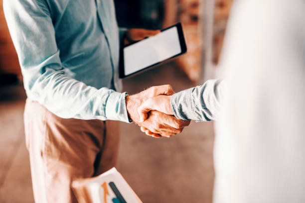 close up of two modern businessman shaking hands for good negotiations and standing in warehouse. - manual worker handshake industry warehouse imagens e fotografias de stock