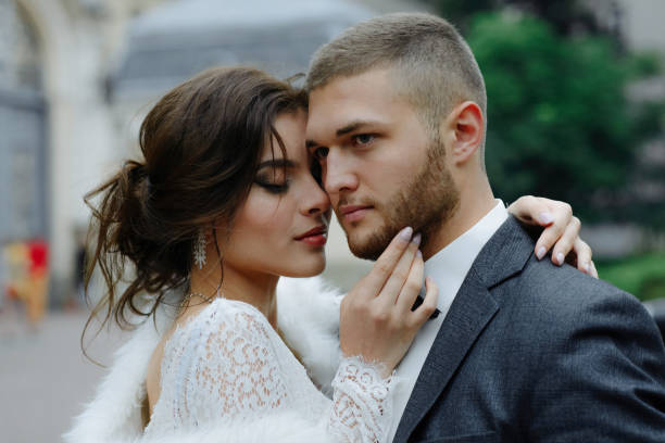 pan młody w szarym garniturze i panna młoda w szarej sukience patrzą na siebie, zbliżenie portret - bride veil women human face zdjęcia i obrazy z banku zdjęć