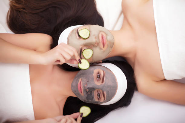 istock Comic young sisters after shower making mask with cucumber 1125033129