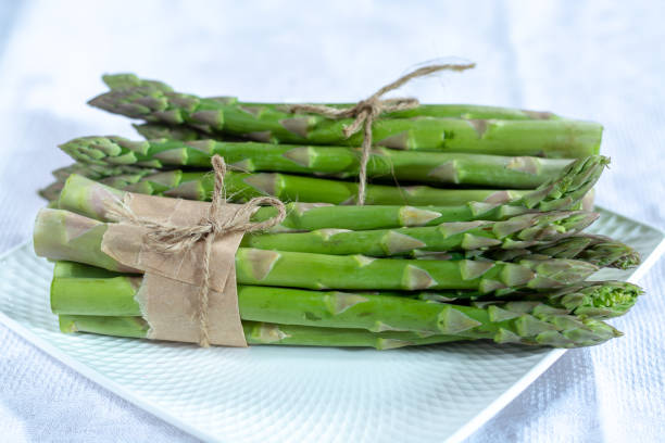 istock Fresh raw green asparagus vegetable on white board, close up 1125035288