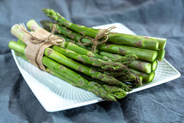 istock Fresh raw green asparagus vegetable on white board, close up 1125035290