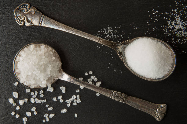 istock Salt, large sea and small kitchen in silver spoons on a black stone background 1125036634