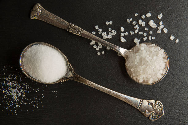 istock Salt, large sea and small kitchen in silver spoons on a black stone background 1125036636