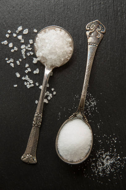 mar de sal, grande e pequena cozinha em colheres de prata sobre um fundo preto e pedra - rock sugar - fotografias e filmes do acervo