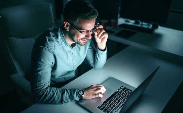istock Happy employee using laptop for working on project while sitting in the office late at night. 1125038613