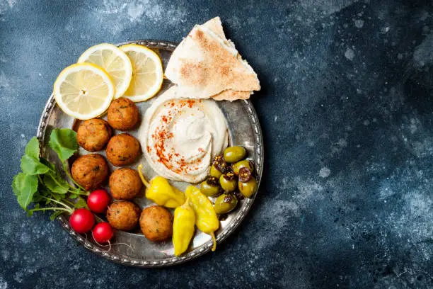 Middle Eastern meze platter with falafel, pita,  hummus, pickles, radishes. Mediterranean or greek appetizer party idea