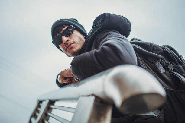 Young, handsome man in black winter clothing, wearing backpack, standing on the stairs.