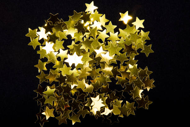 istock Sparkling and holographic golden star confetti on black background. 1125066549