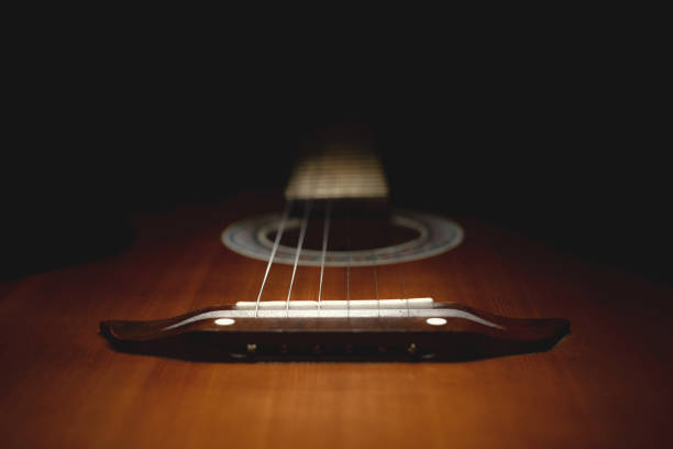 istock part of an old brown guitar with strings on a dark wooden background. Selective focus 1125074493