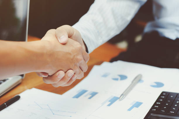 istock Close-up of two business executives shaking hands with data documents on the table 1125076023