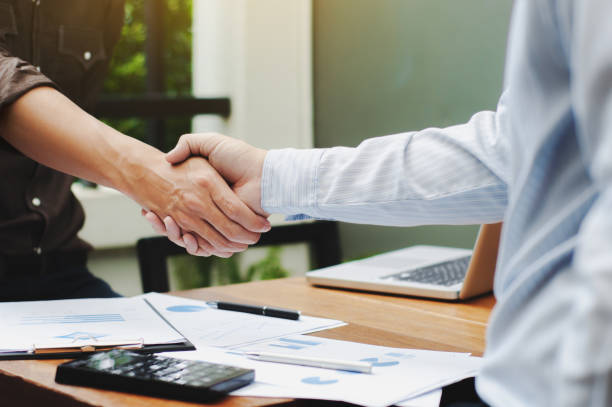 istock Close-up of two business executives shaking hands with data documents on the table 1125076024