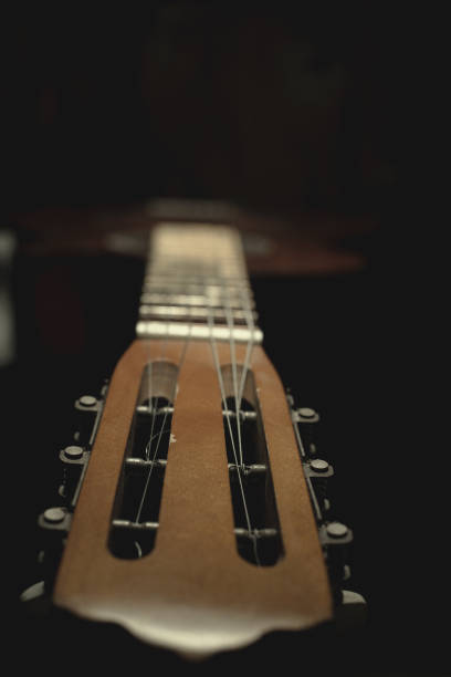 istock part of an old brown guitar with strings on a dark wooden background. Selective focus 1125077231
