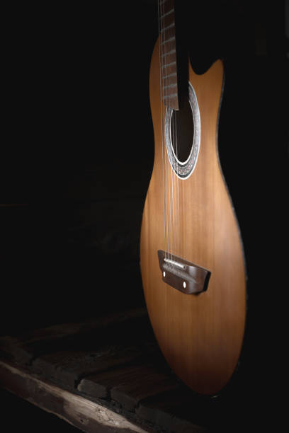 istock part of an old brown guitar with strings on a dark wooden background. Selective focus 1125077269