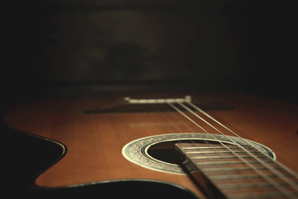 istock part of an old brown guitar with strings on a dark wooden background. Selective focus 1125077373