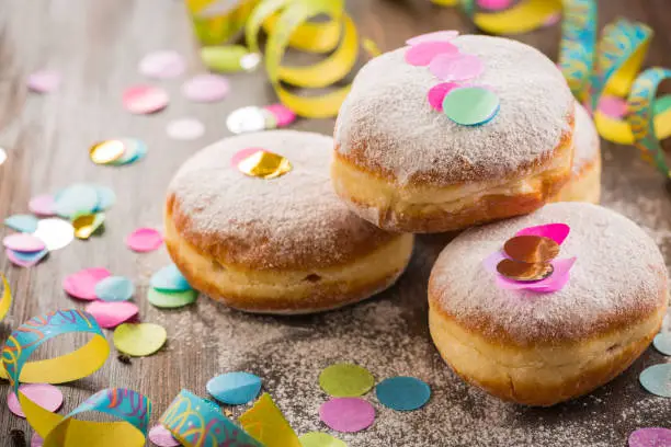 Krapfen, Berliner or  donuts with streamers and confetti. Colorful carnival or birthday image