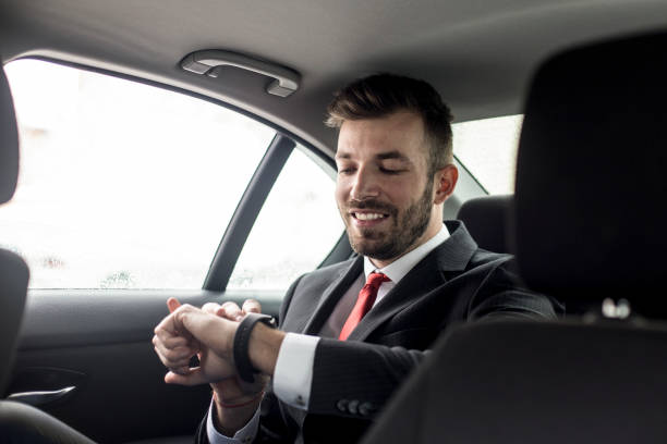 Businessman in taxi Modern businessman driving in a car on the back seat, using a smart watch. About 30 years old, Caucasian male. smart watch business stock pictures, royalty-free photos & images