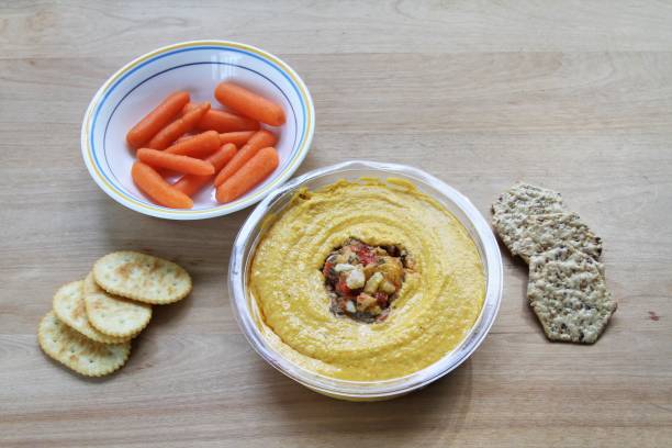 Bowl of hummus dip with crackers and baby carrots