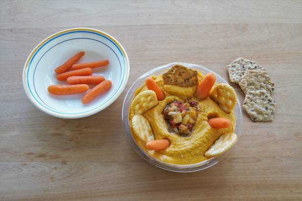 Bowl of hummus dip with crackers and baby carrots