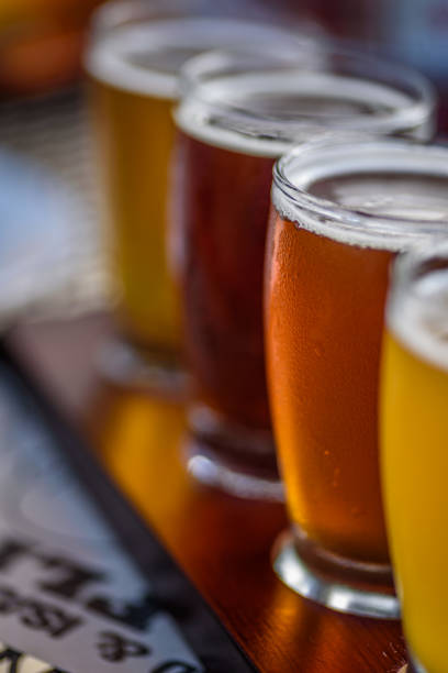 Macro beer flight in sunlight Closeup of craft beer samples on wood paddle outside at microbrewery india pale ale photos stock pictures, royalty-free photos & images