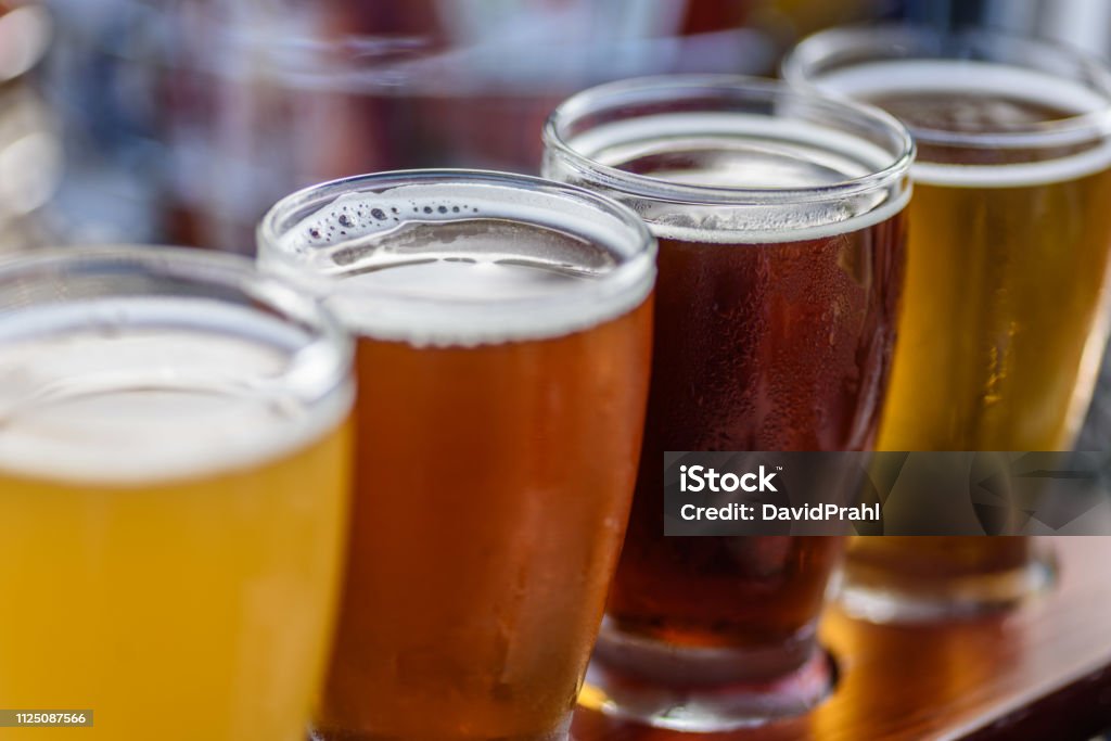 Beer flight in summer sunlight Beautiful colorful beer sample glasses at microbrewery Craft Beer Stock Photo
