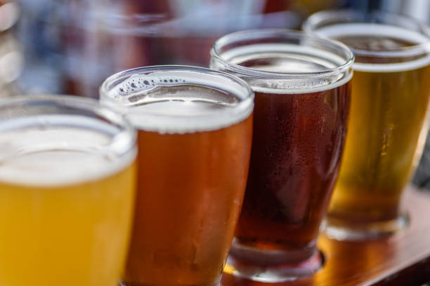 Beer flight in summer sunlight Beautiful colorful beer sample glasses at microbrewery brewery stock pictures, royalty-free photos & images