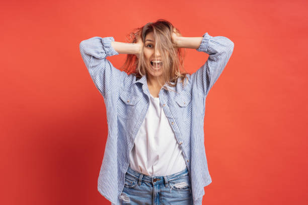 istock Funny, cute girl having fun while playing with hair isolated on a red background 1125090778