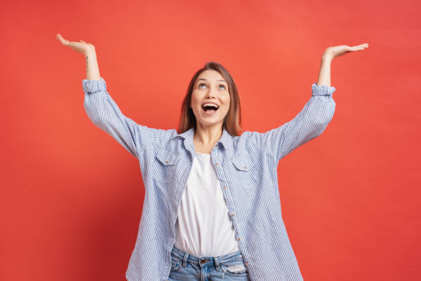 istock Smiling girl having fun isolated on a red background holding hands up smiling gratefully 1125090790