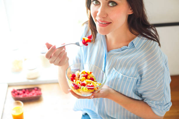 istock Closeup on young housewife eating fresh fruit salad 1125091886