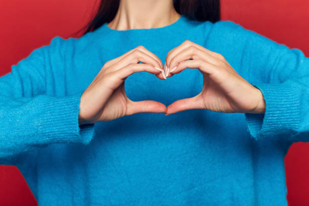 istock Studio portrait of pretty cute tender cheerful nice beautiful attractive charming she her girl making heart on chest isolated on red background 1125093381