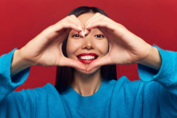 istock Studio portrait of pretty cute tender cheerful nice beautiful attractive charming she her girl making heart on chest isolated on red background 1125093382