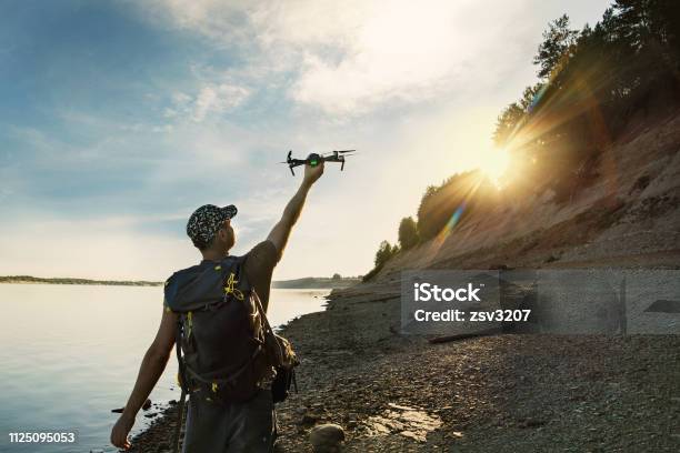 Male Tourist Launching Drone From Hand In Beautiful Sunset In Woodland Stock Photo - Download Image Now