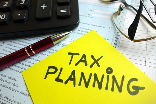 Tax planning text, 1040 form, pen, calculator and eyeglasses