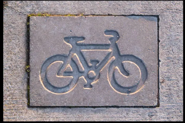 Bicycle bike lane sign cast in concrete in the ground as indication for cyclists and warning for pedestrians