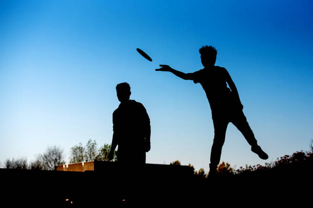 Hand holding yellow frisbee outside. Flaying frisbee outdoors with blue sky in the background