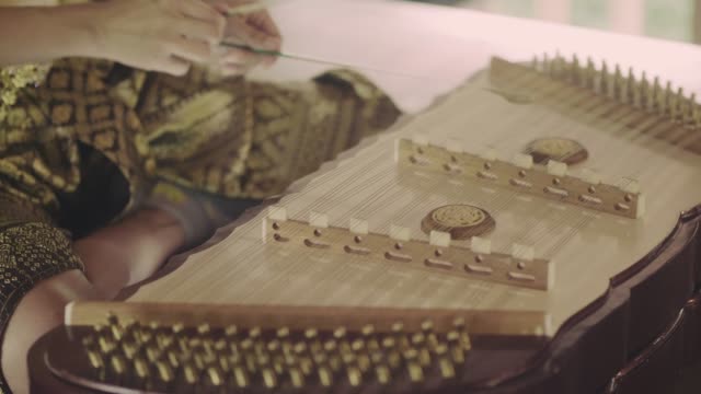 Thai woman playing Thai wooden dulcimer musical instrument