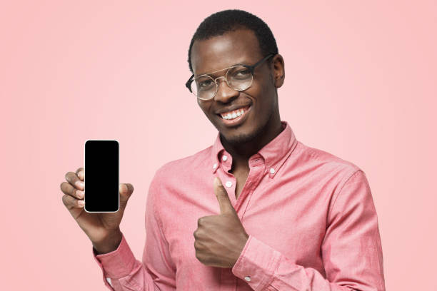 istock Young black man holding blank smartphone, smiling at camera, showing thubms up gesture 1125110892