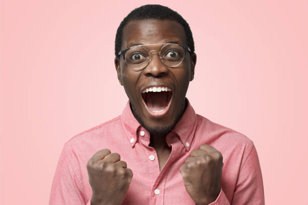 istock Young attractive black man shouting while his team win, raised both fist in victory gesture, isolated on pink background 1125110900