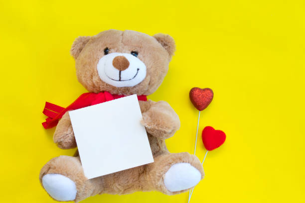 istock Cute teddy bear and card on yellow background.Valentine's day concept. 1125111994