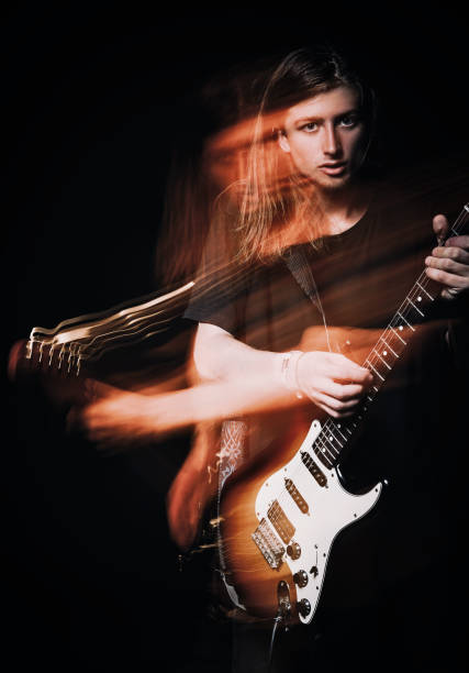 istock Studio portrait: handsome young long haired man (rock musician) playing the electric guitar. Blurry (motion) effect 1125116468