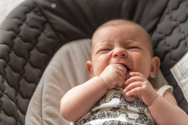 baby liegend und mit den fingern in ihren mund kinderkrankheiten mit ersten zahn draufsicht gesundheitswesen weinen - gezahnt fotos stock-fotos und bilder