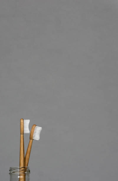istock Two bamboo toothbrushes in glass bottle on yellow background. 1125145157