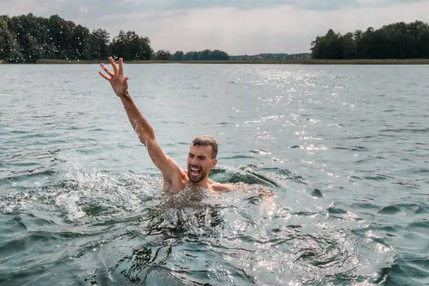 Sinking person calls for help. Hand drowning man sticking out of the water.