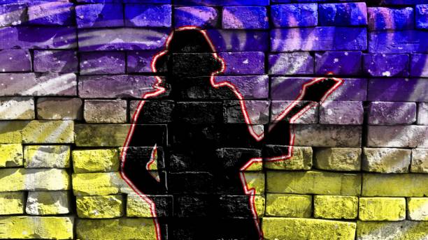 Silhouette of a guitarist in a baseball cap playing the guitar on a bright background. Virtual graffiti. Image, drawn on a photo of a brick wall. stock photo