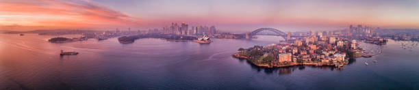 D Kurraba Red U wide pan dawn Red dawn sun light reflecting in waters of Sydney harbour and bays around waterfront of Sydney city CBD with landmarks in wide aerial panorama. sydney harbor stock pictures, royalty-free photos & images