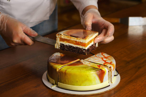istock Confectioner cuts dacquoise cake in mirrored glaze. 1125200728