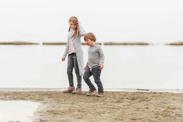 istock Two little kids playing outdoors by the lake, wearing grey clothes 1125203408