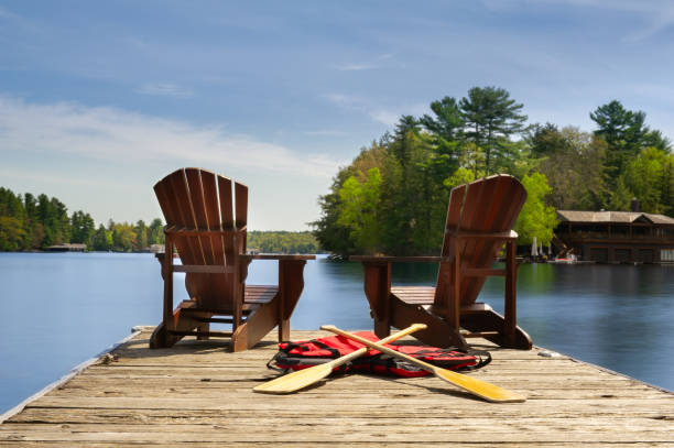 adirondack chairs on a wooden dock facing ta calm lake - cabin imagens e fotografias de stock