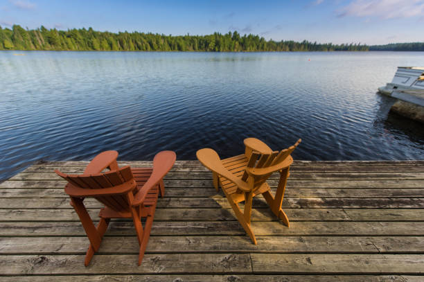 istock Adirondack chairs on a wooden dock facing ta calm lake 1125219779