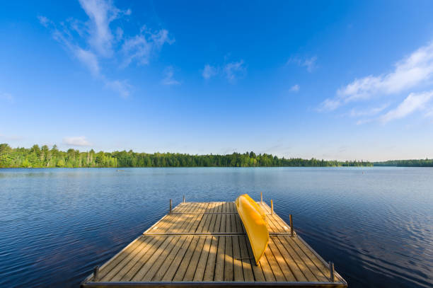 Yellow canoe sitting on a wooden dock at the lake stock photo