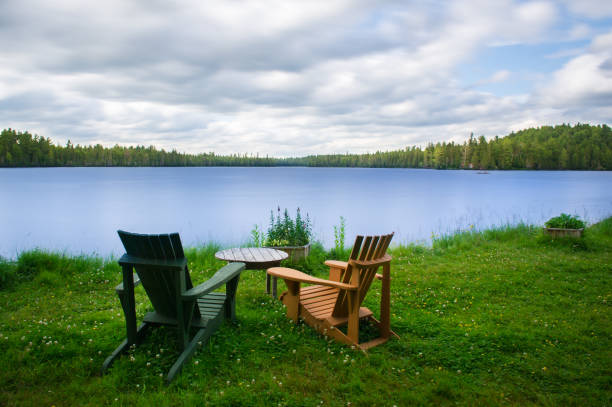 istock Chairs sit on the grass facing a lake waterfront 1125219900